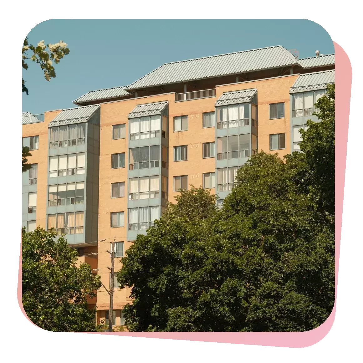 Older condominium building in Oshawa surrounded by mature trees